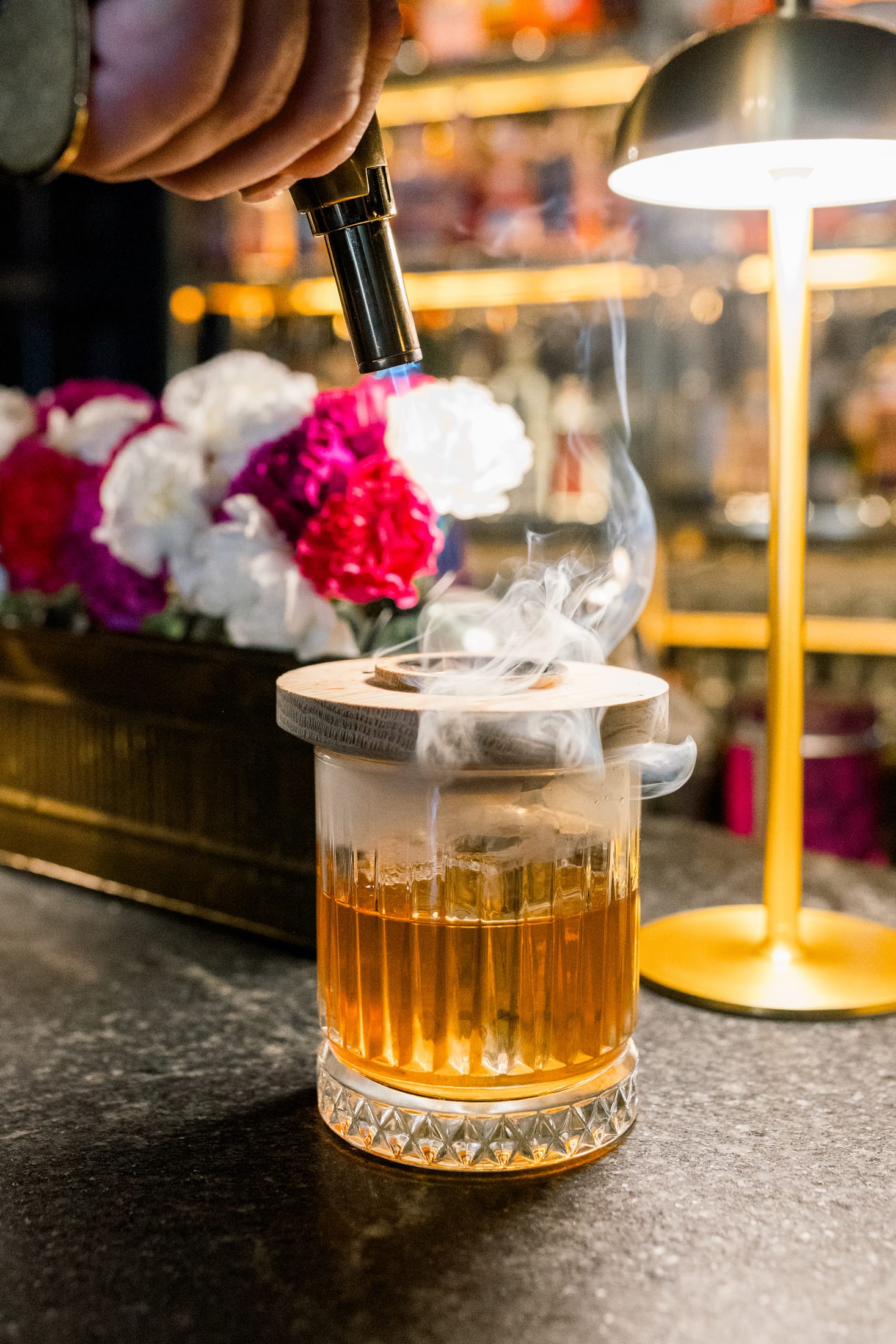 A Sentinel smoker being used over a cocktail